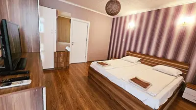 a bedroom with a large bed and a television at Green House Apartment in Burgas City