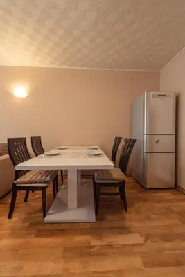 a table with chairs and a refrigerator in a room at Green House Apartment in Burgas City