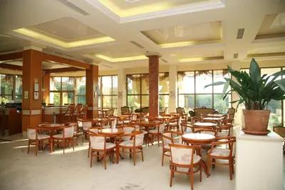a restaurant with wooden tables and chairs and a potted plant at Duni Belleville - All Inclusive in Sozopol