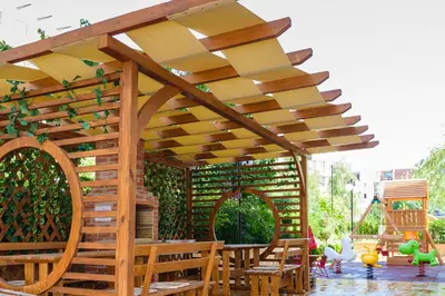 a wooden pergola with tables and chairs under it at Sweet Homes Apartments in Sunny Beach
