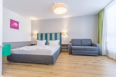 a bedroom with a bed and a blue chair at BSA Boulevard Boutique in Sunny Beach