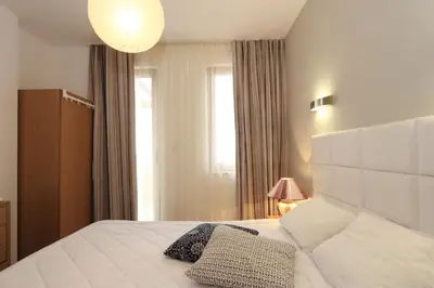 a bedroom with a white bed with a lamp and a window at View Apartments in Sozopol