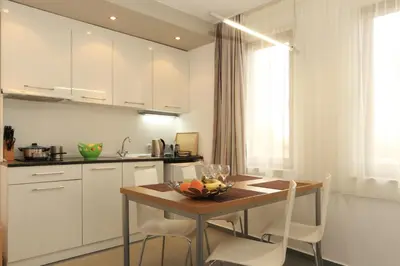 a kitchen with a wooden table and white cabinets at View Apartments in Sozopol