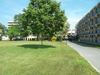 a tree in the grass next to a building at Hotel Pliska - All Inclusive Light in Sunny Beach