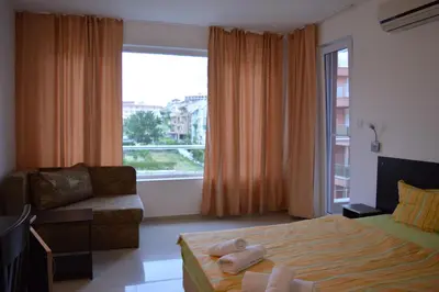 a bedroom with a bed and a couch and a window at Hotel Paradise in Lozenets