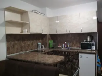 a kitchen with white cabinets and a granite counter top at Виктория in Pomorie