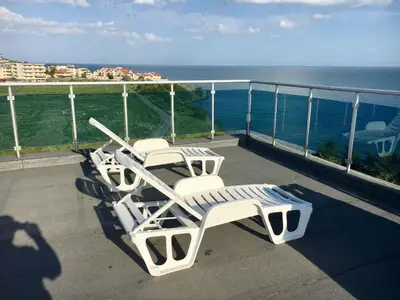 a row of lounge chairs on a balcony overlooking the ocean at DEA Pasavan Apartments in Ravda