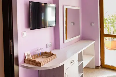 a bathroom with a vanity with a mirror and purple walls at Kirios Hotel in Nesebar