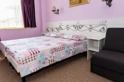 a bedroom with a bed and a desk and a chair at Kirios Hotel in Nesebar