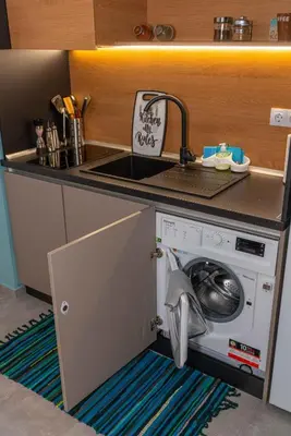 a kitchen with a washing machine under a counter at Pomorie Seaside Apartments in Pomorie