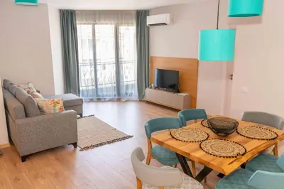 a living room with a wooden table and chairs at Pomorie Seaside Apartments in Pomorie