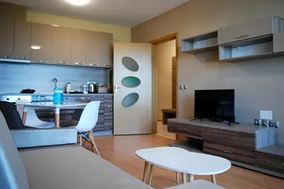 a living room with a table and a kitchen at Dune Boutique Pomorie in Pomorie