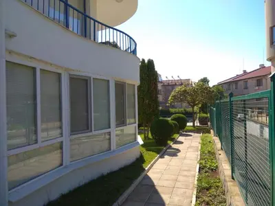 a building with windows and a fence next to a sidewalk at Blue Marine Ap 26 in Ravda