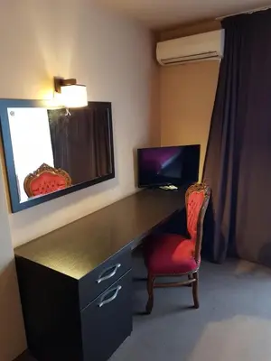 a desk with a red chair in a room at Family Hotel Vaso in Varna City