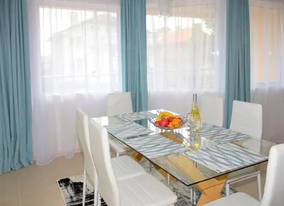 a dining room with a glass table and white chairs at Rusalka Apart-Residence in Obzor