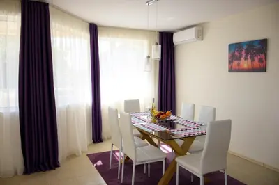 a dining room with a table and white chairs at Rusalka Apart-Residence in Obzor