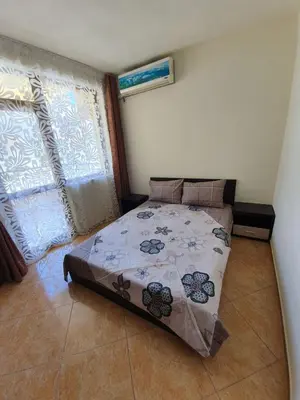 a bedroom with a bed in a room with windows at Виктория Созопол in Sozopol