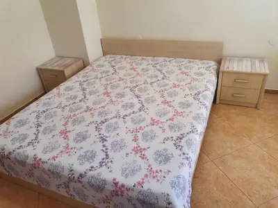 a bedroom with a bed with a floral bedspread at Виктория Созопол in Sozopol