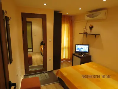 a bedroom with a bed and a mirror and a television at Family Hotel Lebed in Nesebar