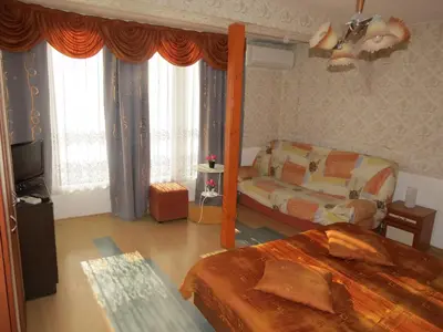 a bedroom with a bed and a couch and a tv at Family Hotel Lebed in Nesebar