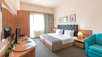 a hotel room with a bed and a desk at Lotus Family Hotel - Free Parking in Sunny Beach