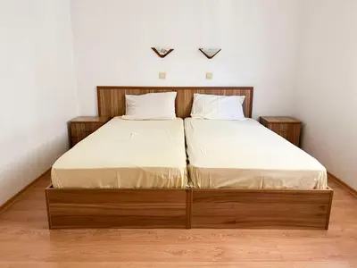 a bed with a wooden frame and white sheets at Комплекс «ТОП» in Sveti Vlas