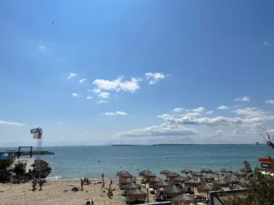 a beach with umbrellas and people on the beach at Комплекс «ТОП» in Sveti Vlas
