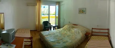 a bedroom with a bed and a tv and a window at Harmony Beach Family Hotel in Nesebar