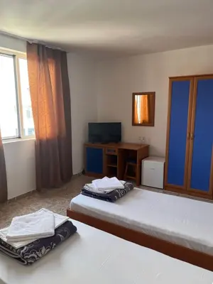 a bedroom with two beds and a desk and a television at Къща Нанси in Sunny Beach