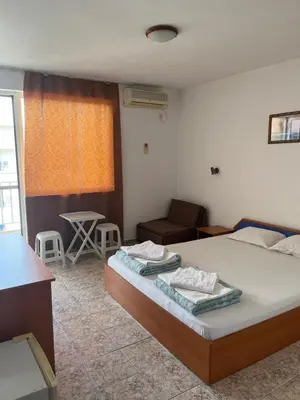 a bedroom with a bed and a couch and a table at Къща Нанси in Sunny Beach