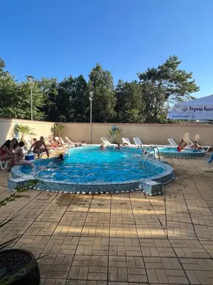 a large swimming pool with people sitting around it at Къща Нанси in Sunny Beach