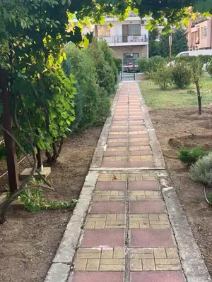 a walkway in a garden with trees and bushes at Lilia Guest House in Nesebar