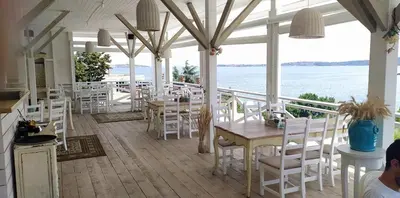 a restaurant with white chairs and tables and the ocean at FLORES GARDEN SEA VIEW APARTMENT WITH BALCONY in Chernomorets