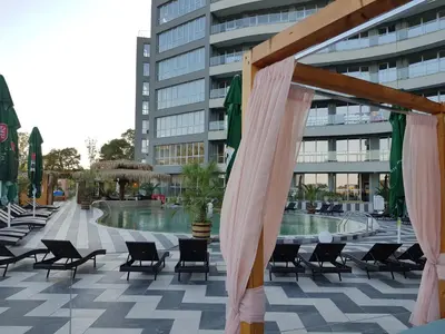 a patio with chairs and a pool in front of a building at Allure Beach Resort Aparthotel in Primorsko