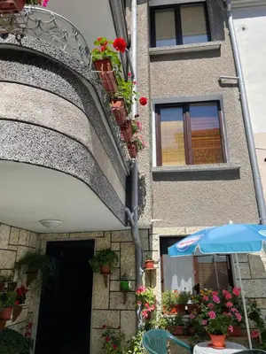 a building with flowers and an umbrella in front of it at Mariana Guest House Къща за гости Марияна in Pomorie