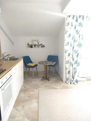 a kitchen with a table and two blue chairs at White Rose Guest Rooms in Burgas City