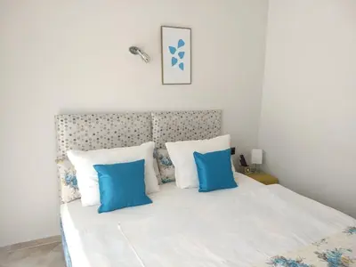 a bedroom with a white bed with blue pillows at White Rose Guest Rooms in Burgas City