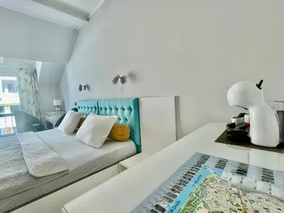 a white bedroom with a bed with a blue headboard at White Rose Guest Rooms in Burgas City