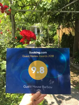 a person holding a card with a guest house barrow at Guest House Barbov in Obzor
