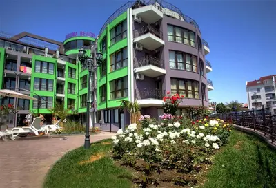 a green building with flowers in front of it at Laguna Beach Hotel in Ravda