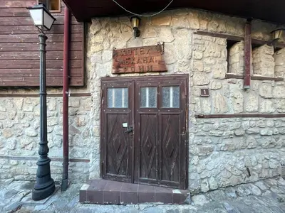 a stone building with a wooden door and a street light at Rony Hotel in Nesebar