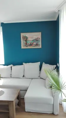 a living room with a white couch and a blue wall at Azur Apartment Deluxe in Chernomorets