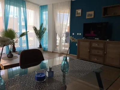 a living room with a tv and a vase on a table at Azur Apartment Deluxe in Chernomorets
