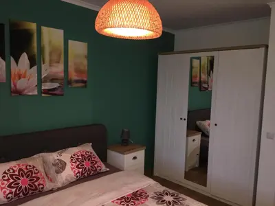 a bedroom with green walls and a bed and a chandelier at Azur Apartment Deluxe in Chernomorets
