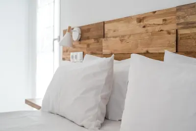 a bedroom with white pillows and a wooden headboard at Camping Gradina in Sozopol