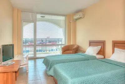 a hotel room with two beds and a television at South Beach Vacation Apartments in Sunny Beach