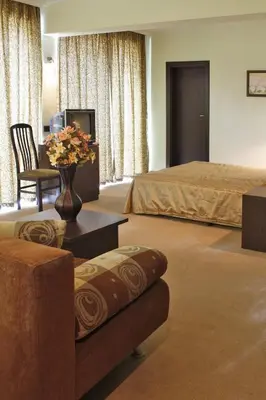 a hotel room with a bed and a vase of flowers at Hotel Dukov in Obzor