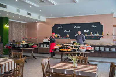 a restaurant with two people standing in front of a buffet at Mercury Hotel- All Inclusive in Sunny Beach