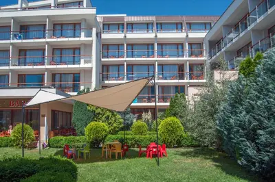 an apartment building with a yard with tables and chairs at Mercury Hotel- All Inclusive in Sunny Beach