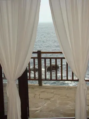 a room with a view of the ocean through curtains at Deep Blue Guest House in Sozopol